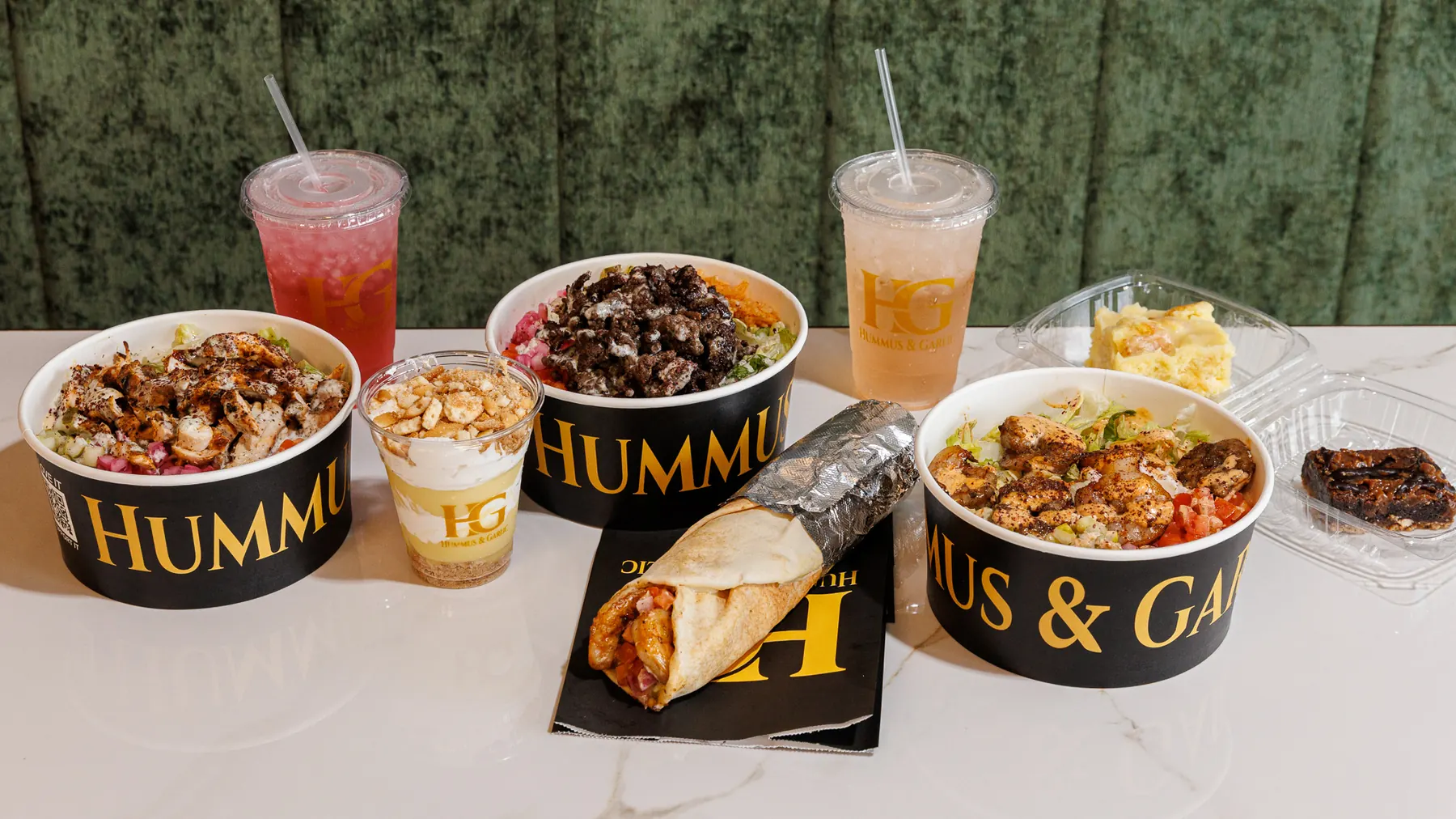 Bowls, a shawarma wrap, a parfait and two lemonades spread across the marble counter